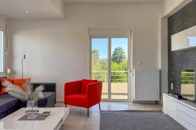 a living room with a red chair and a fireplace at Villa Adam in Chania Town