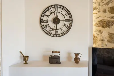 a clock on a wall above a shelf with vases at Villa Eleftheria in Áyios Yeóryios