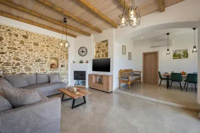 a living room with a couch and a tv at Villa Eleftheria in Áyios Yeóryios