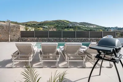 a grill on a patio with chairs and a pool at Casa Nougia in Chania Town