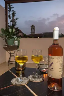 a bottle of wine and two glasses on a table at Splatzia old town maizonette in Chania Town