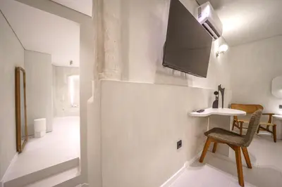 a room with a chair and a table and a tv at Amelia Luxury Suites Old Town in Chania Town