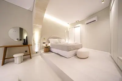 a white bedroom with a bed and a mirror at Amelia Luxury Suites Old Town in Chania Town