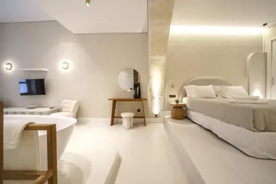 a white bedroom with a bed and a tub and a sink at Amelia Luxury Suites Old Town in Chania Town
