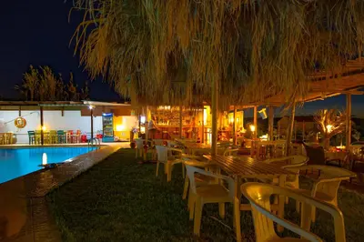 a restaurant with chairs and a pool at night at Andy's Gardens in Gerani Chanion