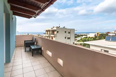 a balcony with a chair and a view of the ocean at Alpha delight apartment 3 bedroom in Chania Town