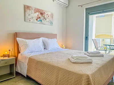 a bedroom with a large bed and a balcony at Newly Built House Steps from the Beach: Everything Within Walking Distance - Enjoy a Car-Free Stay in Agia Marina Nea Kydonias