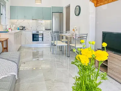 a kitchen and a living room with a table and yellow flowers at Newly Built House Steps from the Beach: Everything Within Walking Distance - Enjoy a Car-Free Stay in Agia Marina Nea Kydonias