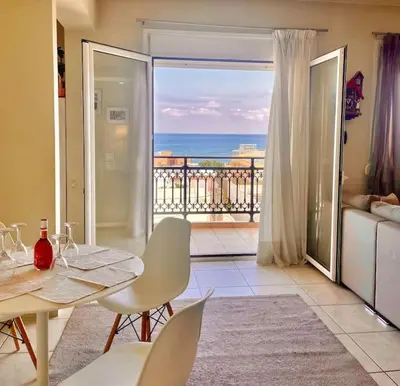 a living room with a table and chairs and a balcony at Sea View Apartment #1 in Ayiá