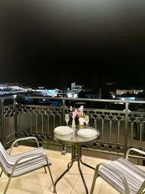 a table with two chairs and wine glasses on a balcony at Sea View Apartment #1 in Ayiá
