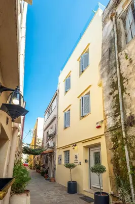 a street with a yellow building and two potted trees at s - plazza residence in Chania Town