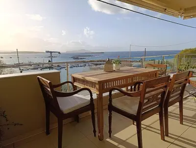 a wooden table and chairs on a balcony with a view of the ocean at Ferienwohnung am Meer Belle Vue in Chania Town