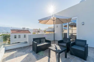 a patio with two chairs and an umbrella on a roof at Odyssey Residences in Chania Town