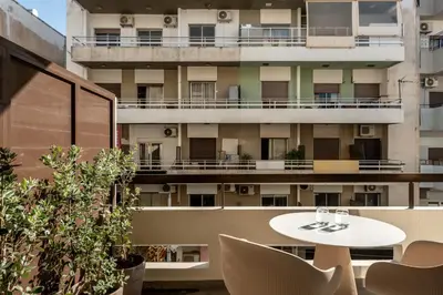 a balcony with a table and chairs and a building at Zakro Luxury Living Chania in Chania Town