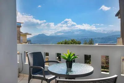 a table and chairs on a balcony with a view of mountains at Glikanisos House Nipos - ideal for hikers and families 2bd, 6pl, 10min to beach in Nípos