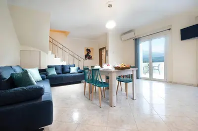 a living room with a couch and a table with chairs at Glikanisos House Nipos - ideal for hikers and families 2bd, 6pl, 10min to beach in Nípos