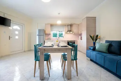 a kitchen and dining room with a table and a blue couch at Glikanisos House Nipos - ideal for hikers and families 2bd, 6pl, 10min to beach in Nípos