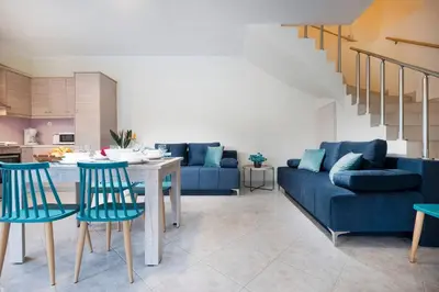 a living room with a blue couch and a table and chairs at Glikanisos House Nipos - ideal for hikers and families 2bd, 6pl, 10min to beach in Nípos