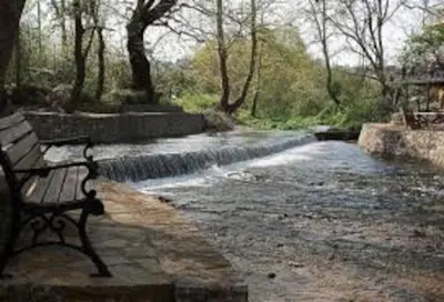 a park bench sitting in front of a stream at apartment irini in Vryses