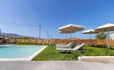 a group of chairs and umbrellas next to a pool at Achatis Apartments with sea view in Kolymvari
