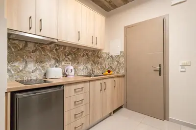 a small kitchen with wooden cabinets and a door at Achatis Apartments with sea view in Kolymvari