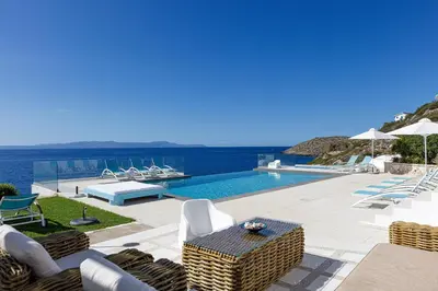 a pool with chairs and a table with a view of the ocean at Villa Chryssi in Tersanas