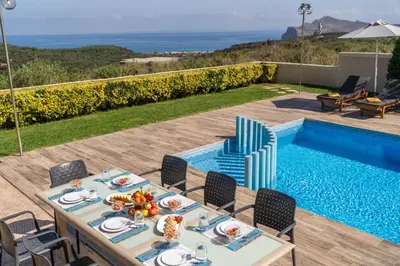 a table and chairs next to a swimming pool at Villa Ariella With Sea View in Agia Marina Nea Kydonias