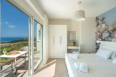 a bedroom with a bed and a table and a balcony at Villa Ariella With Sea View in Agia Marina Nea Kydonias
