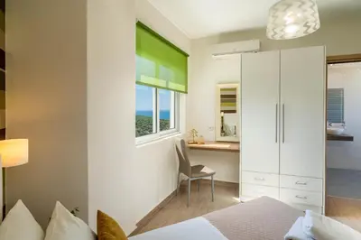 a bedroom with a bed and a desk and a window at Villa Ariella With Sea View in Agia Marina Nea Kydonias