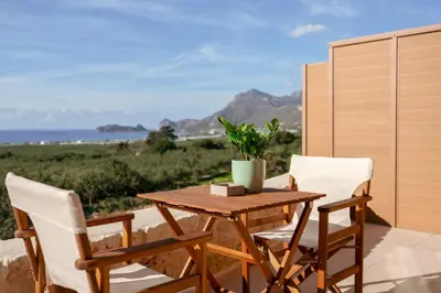 a wooden table and chairs on a patio with the ocean at Anadia Luxury Pocket Villa Infinite Sea View in Falasarna