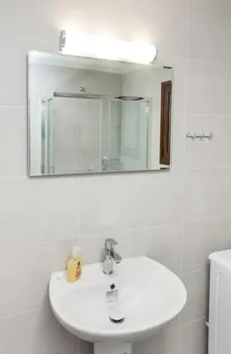 a white bathroom with a sink and a mirror at Kalliston City House with a Yard in Chania Town
