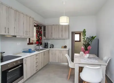 a kitchen with white cabinets and a table and chairs at Kalliston City House with a Yard in Chania Town