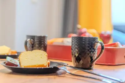 a table with two coffee cups and a piece of cake at MOS Luxury Suits 