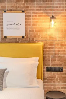 a bed with a yellow headboard next to a brick wall at MOS Luxury Suits 