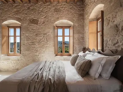a bedroom with a large bed in a stone wall at Corte Interna, free heated pool in Kalivianí