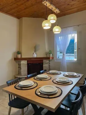 a dining room table with chairs and a fireplace at Olives Villa in Anopoli Sfakion