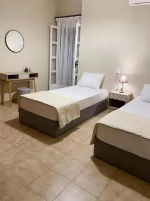 a bedroom with two beds and a desk and a mirror at Olives Villa in Anopoli Sfakion