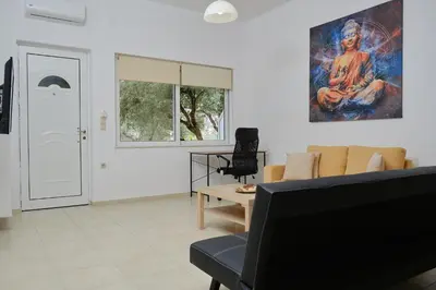 a living room with a couch and a painting on the wall at AVRA COZY APARTMENT Agioi Apostoloi Chania in Daratso