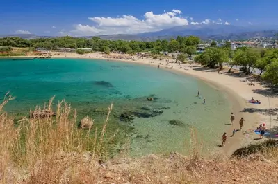 a beach with a group of people in the water at AVRA COZY APARTMENT Agioi Apostoloi Chania in Daratso