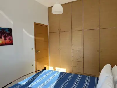 a bedroom with a bed and wooden cabinets at AVRA COZY APARTMENT Agioi Apostoloi Chania in Daratso