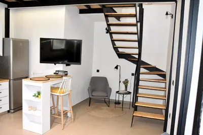 a room with a tv and a spiral staircase at Gkerola house - small cozy house close to Chania town center in Chania Town