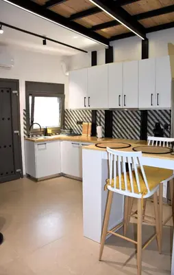 a kitchen with white cabinets and a wooden table and chair at Gkerola house - small cozy house close to Chania town center in Chania Town