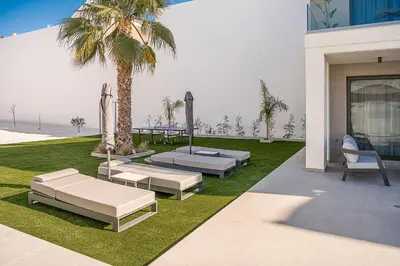 a patio with two beds and a palm tree at Mossa Concept Villas - heated pool- 200 m from the beach in Daratso