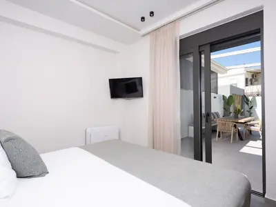 a white bedroom with a bed and a balcony at Mossa Concept Villas - heated pool- 200 m from the beach in Daratso