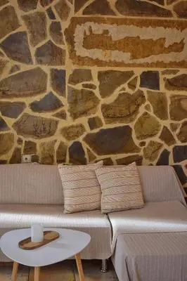 a living room with a couch and a stone wall at Κρητικό παραδοσιακό διαμέρισμα! in Chania Town