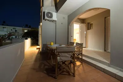 a dining table and chairs on a balcony at night at Zoe's Place - 1 BD Beachfront Apartment in Kissamos
