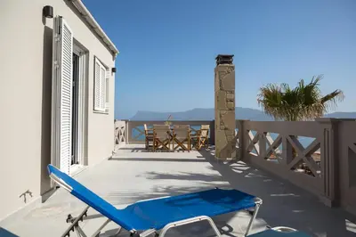 a blue chair on a balcony with a table at Zoe's Place - 1 BD Loft Beachfront Apartment in Kissamos