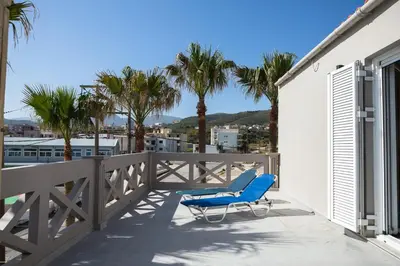 a blue chair on a balcony with palm trees at Zoe's Place - 1 BD Loft Beachfront Apartment in Kissamos