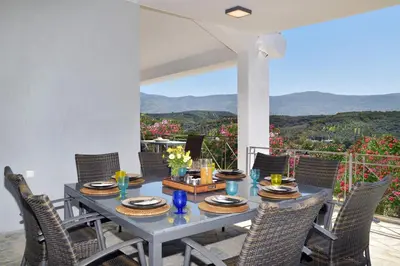 a dining table and chairs on a patio with a view at Villa Raks in Kántanos
