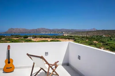 a guitar and a chair on a balcony with a view at Sea Apt - Akrotiri in Kounoupidhianá